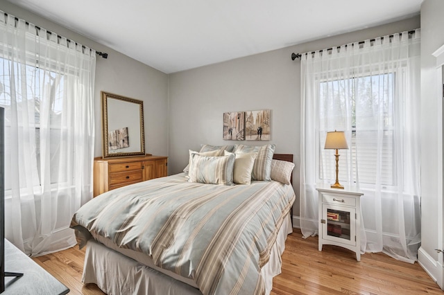 bedroom with multiple windows and light wood-style flooring