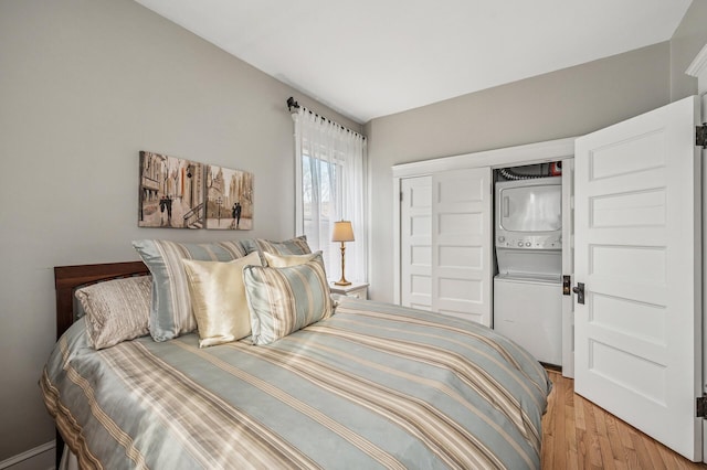 bedroom featuring a closet, light wood-style floors, and stacked washer / dryer