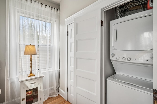 laundry area with laundry area, stacked washer / drying machine, and light wood-style floors