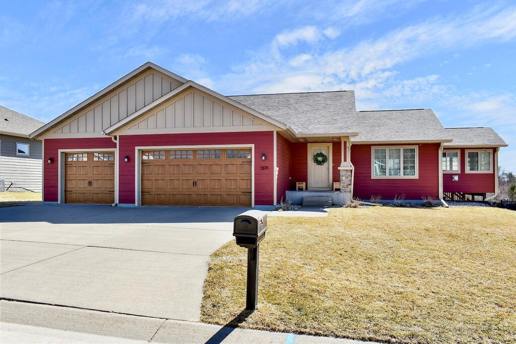 view of front of property with board and batten siding, concrete driveway, a garage, and a front lawn