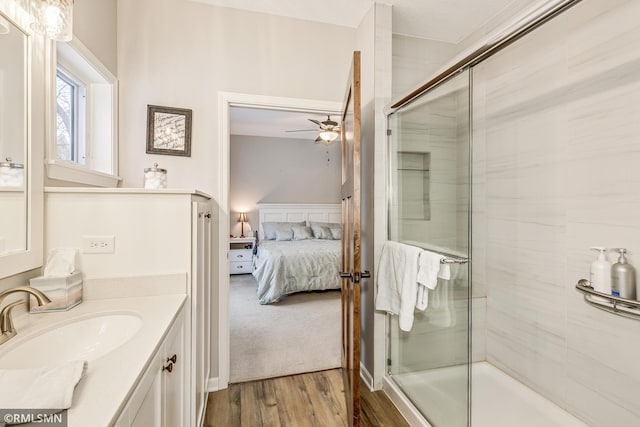 ensuite bathroom with ensuite bathroom, a ceiling fan, a shower stall, vanity, and wood finished floors