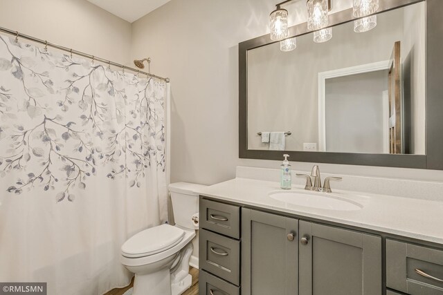 bathroom featuring toilet, curtained shower, and vanity