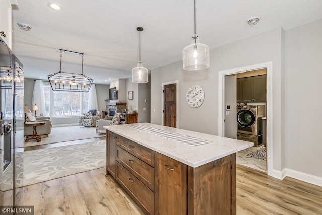 kitchen with open floor plan, light wood finished floors, decorative light fixtures, and a center island