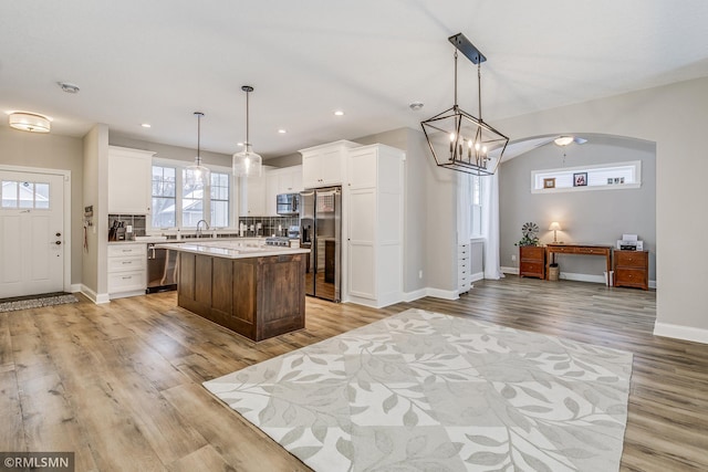 kitchen featuring appliances with stainless steel finishes, backsplash, a kitchen island, and white cabinets