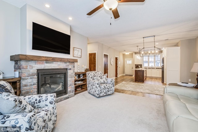 living room with light colored carpet, a glass covered fireplace, a ceiling fan, and recessed lighting