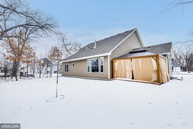 view of snow covered exterior with a shingled roof