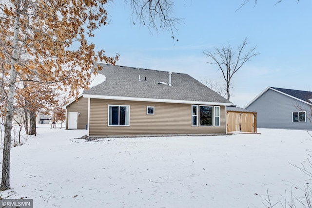 snow covered house featuring a shingled roof