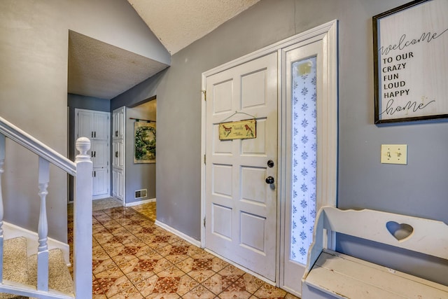 foyer featuring visible vents, vaulted ceiling, a textured ceiling, baseboards, and stairs