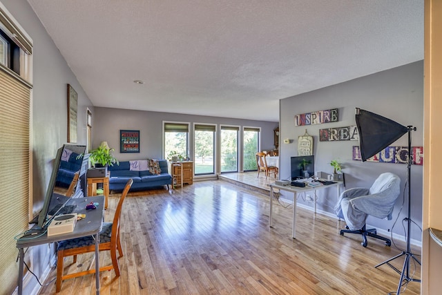 living room featuring a textured ceiling, baseboards, and wood finished floors