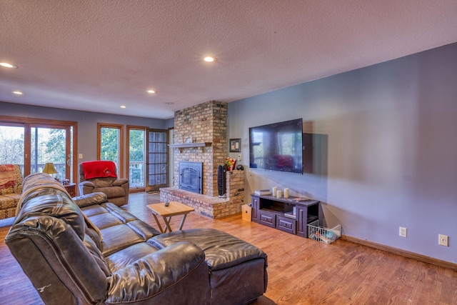 living room featuring a fireplace, recessed lighting, a textured ceiling, wood finished floors, and baseboards