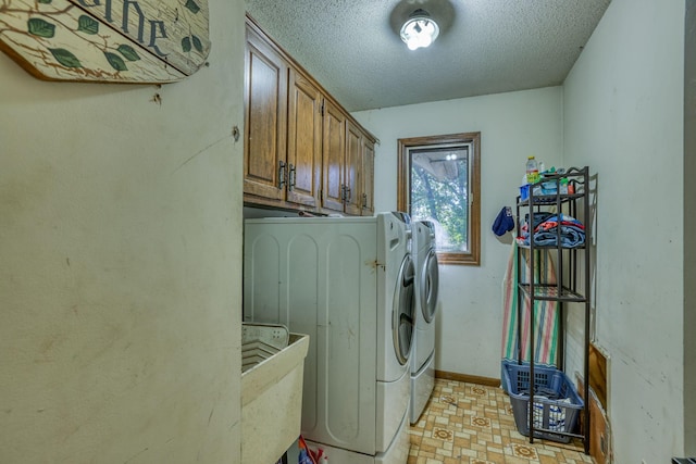 laundry area with cabinet space, baseboards, washer and clothes dryer, and a textured ceiling