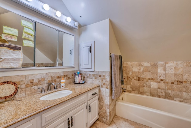 full bath with lofted ceiling, a garden tub, vanity, tile walls, and tile patterned floors