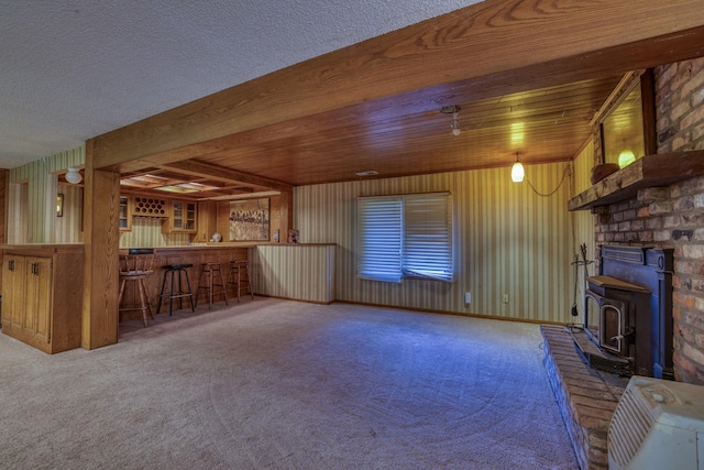 unfurnished living room with a dry bar, a wood stove, and carpet