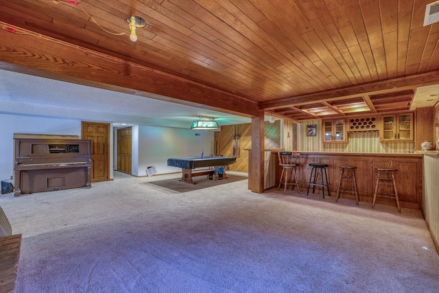 recreation room with carpet floors, bar, beamed ceiling, and wood walls