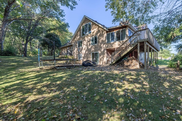 view of side of home with a trampoline, a lawn, a wooden deck, and stairs