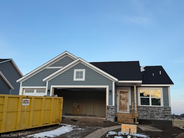 view of front facade featuring a garage, stone siding, and fence