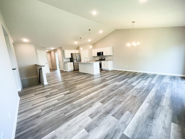 kitchen featuring open floor plan, a kitchen island with sink, stainless steel appliances, white cabinetry, and a notable chandelier