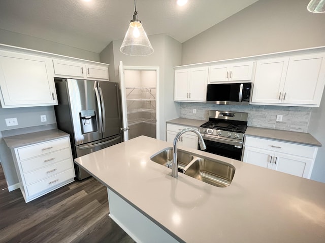 kitchen with white cabinets, lofted ceiling, appliances with stainless steel finishes, a sink, and backsplash