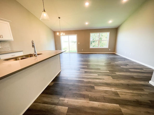 kitchen with lofted ceiling, dark wood-style floors, decorative light fixtures, white cabinetry, and a sink