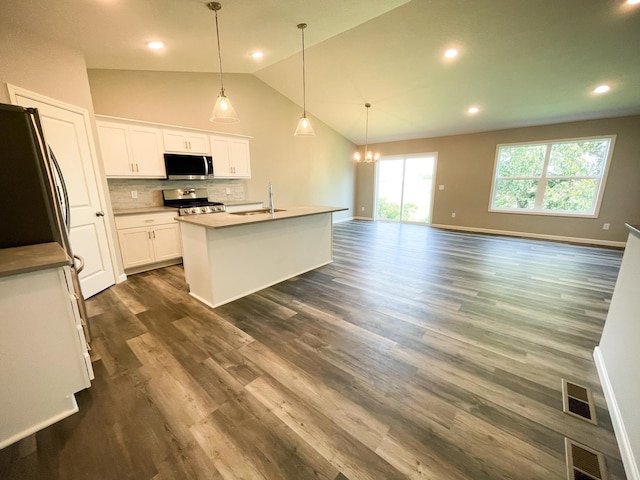 kitchen featuring a sink, visible vents, appliances with stainless steel finishes, decorative backsplash, and dark wood-style floors