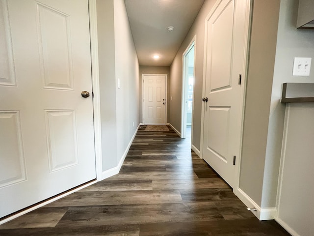 corridor with dark wood-style floors and baseboards