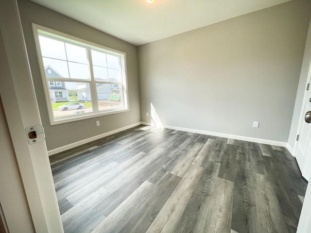 spare room featuring dark wood-type flooring and baseboards