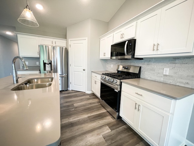 kitchen with dark wood finished floors, backsplash, appliances with stainless steel finishes, white cabinetry, and a sink