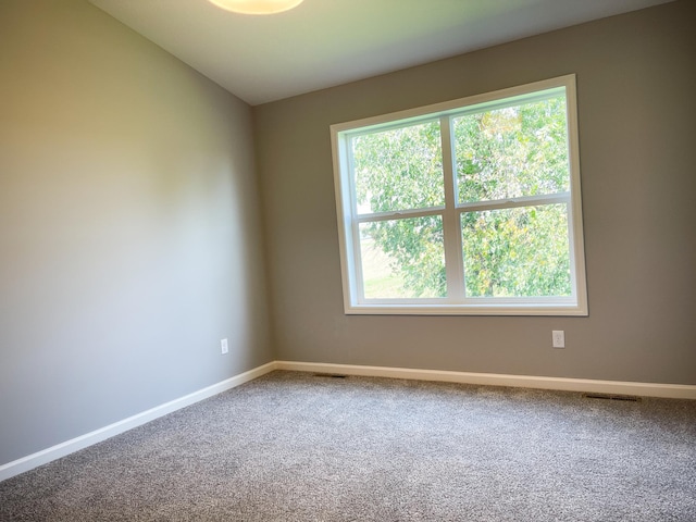 carpeted empty room with lofted ceiling, visible vents, and baseboards