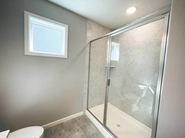 bathroom with a wealth of natural light, a stall shower, toilet, and baseboards