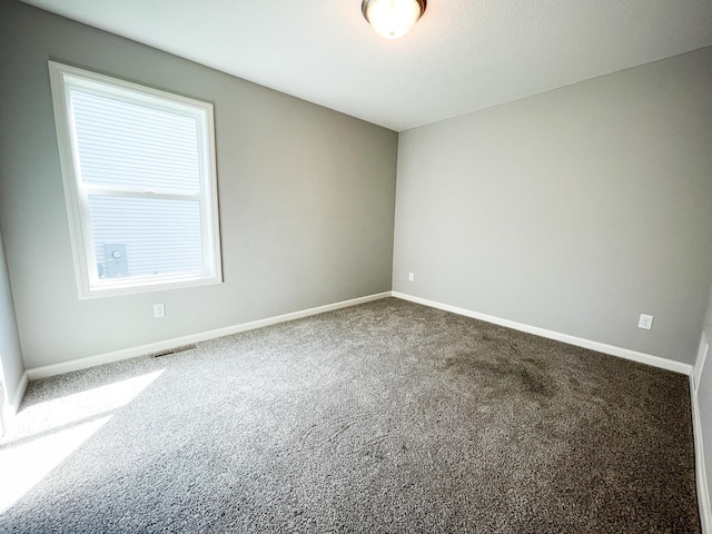 carpeted empty room with visible vents and baseboards