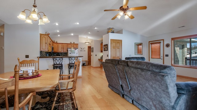 dining room featuring lofted ceiling, baseboards, a ceiling fan, and light wood-style floors