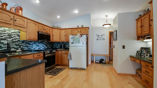 kitchen with stainless steel appliances, dark countertops, lofted ceiling, and light wood-style flooring