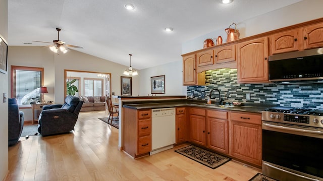 kitchen featuring lofted ceiling, stainless steel appliances, a peninsula, a sink, and dark countertops