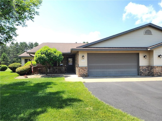 E5751 816th Ave, Tainter Twp, WI 54730 - view of front of home with brick siding, an attached garage, asphalt driveway, and a front lawn