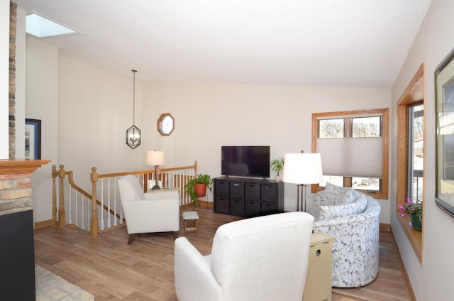 living room featuring lofted ceiling, wood finished floors, and baseboards