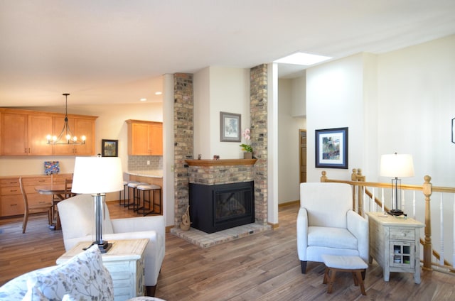 living area featuring a brick fireplace, a notable chandelier, recessed lighting, and light wood finished floors