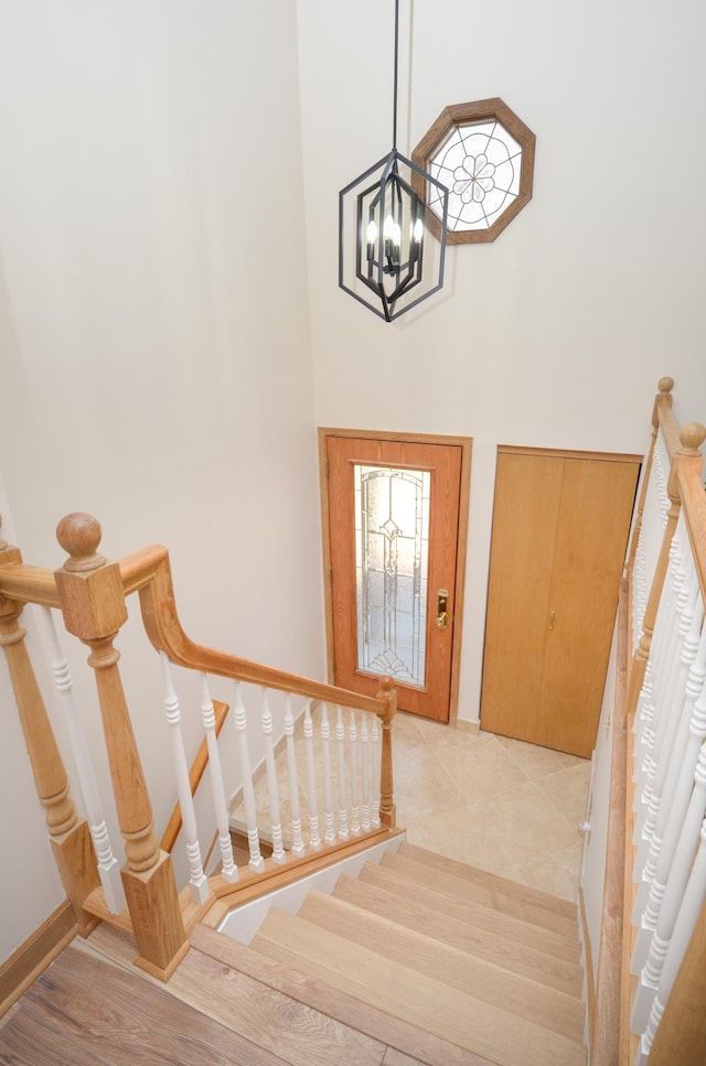 foyer featuring tile patterned floors, a notable chandelier, baseboards, a towering ceiling, and stairs