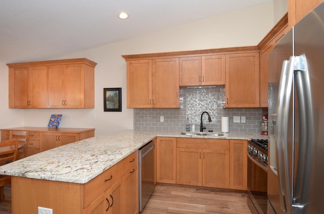 kitchen with light wood-type flooring, a sink, appliances with stainless steel finishes, lofted ceiling, and light stone countertops