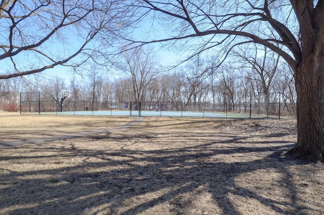 view of yard featuring a tennis court and fence