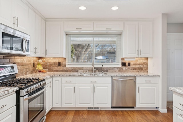 kitchen featuring visible vents, light wood finished floors, a sink, appliances with stainless steel finishes, and white cabinetry