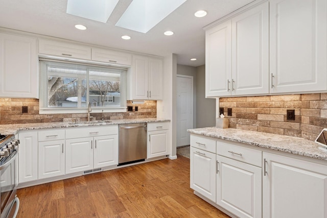 kitchen with visible vents, light wood-style flooring, appliances with stainless steel finishes, a skylight, and a sink