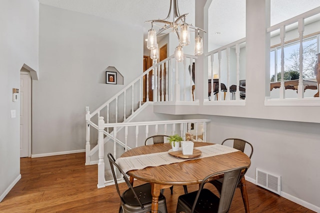 dining space featuring visible vents, baseboards, an inviting chandelier, wood finished floors, and arched walkways