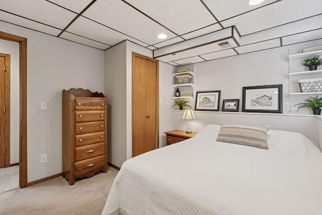 bedroom with visible vents, a closet, baseboards, carpet, and a paneled ceiling