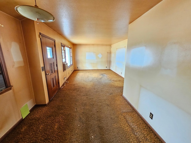 interior space with a textured ceiling, carpet flooring, visible vents, and baseboards