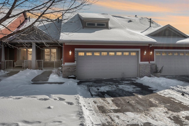 view of front of home with a garage, a porch, and brick siding