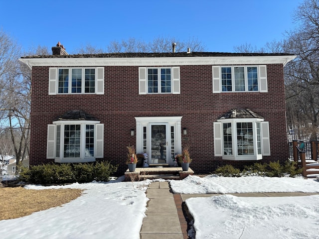 colonial-style house with brick siding and a chimney