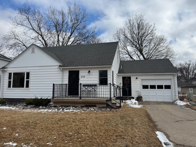 ranch-style home with a shingled roof, a front yard, an attached garage, and aphalt driveway