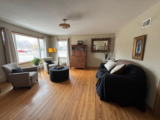 living room with light wood finished floors, baseboards, and visible vents