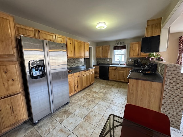 kitchen featuring a sink, black dishwasher, stainless steel refrigerator with ice dispenser, decorative backsplash, and dark countertops