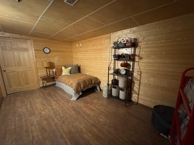 bedroom with hardwood / wood-style floors and wooden walls